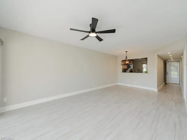 Unfurnished living room featuring ceiling fan with notable chandelier