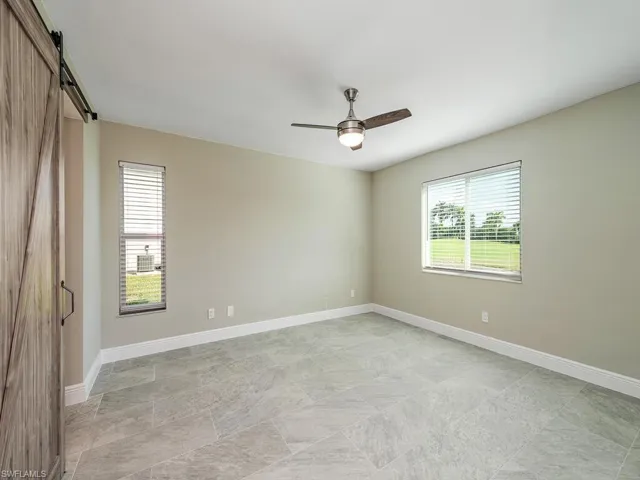 Unfurnished room with ceiling fan and a barn door