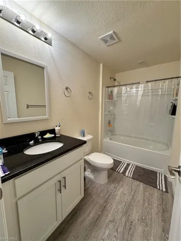 Bathroom with visible vents, a textured wall, shower / bathing tub combination, a textured ceiling, and wood finished floors