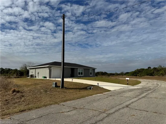 View of front of home featuring a garage, a front yard, concrete driveway, and stucco siding