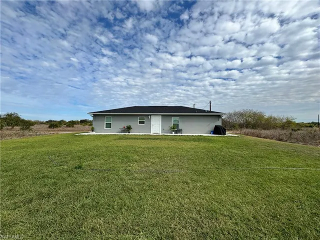 Rear view of house featuring a lawn and stucco siding