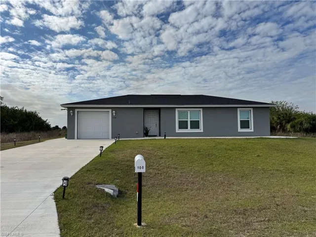 Ranch-style house featuring a garage, concrete driveway, a front yard, and stucco siding