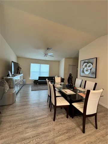 Dining room with baseboards, visible vents, ceiling fan, wood finished floors, and vaulted ceiling