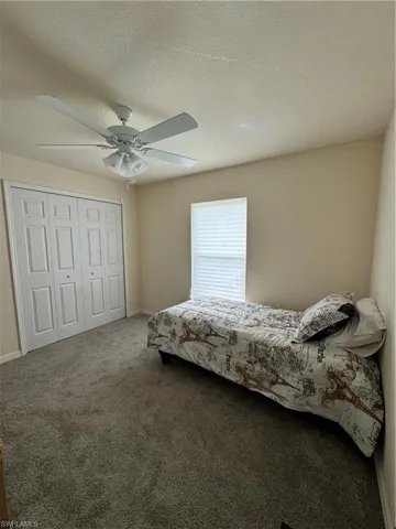 Bedroom featuring a textured ceiling, ceiling fan, carpet flooring, baseboards, and a closet