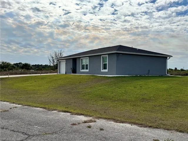 View of side of home featuring a garage, a yard, and stucco siding