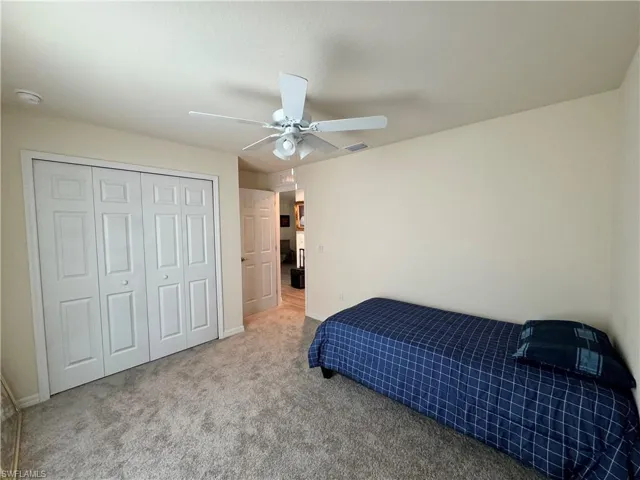 Bedroom featuring ceiling fan, carpet flooring, visible vents, baseboards, and a closet