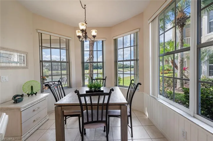 Dining area featuring a chandelier, light tile patterned floors, and a wainscoted wall
