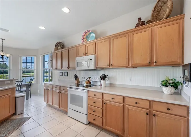 Kitchen featuring white appliances, light countertops, light tile patterned floors, decorative light fixtures, and recessed lighting