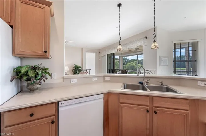 Kitchen with dishwasher, a sink, light countertops, and hanging light fixtures