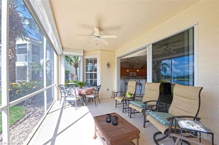 Sunroom / solarium with ceiling fan, a textured wall, and carpet