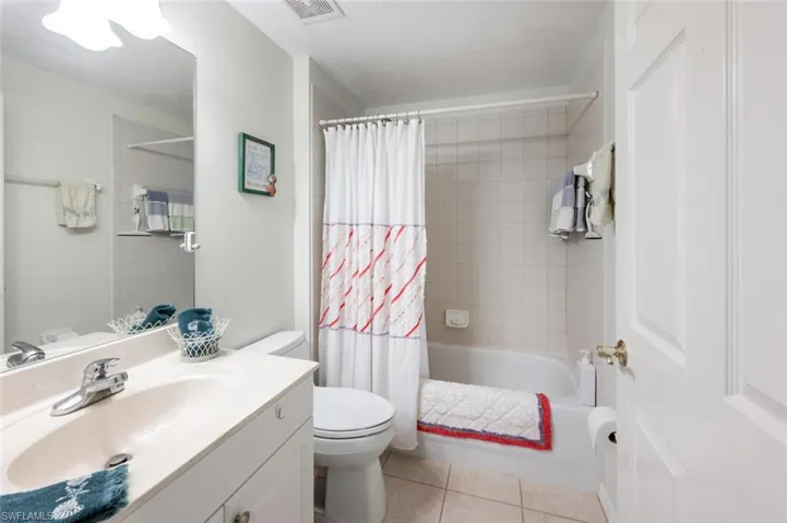 Guest Bathroom featuring toilet, tile patterned floors, vanity, and shower / bath combo with shower curtain