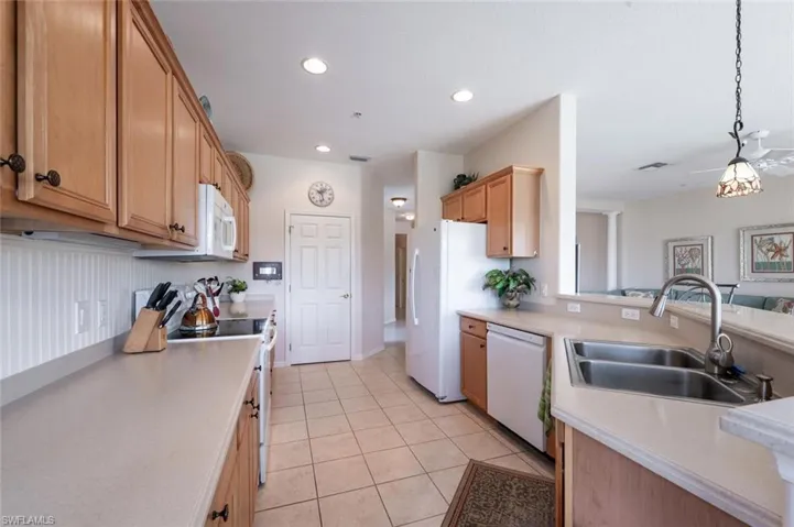 Kitchen featuring white appliances, a sink, light countertops, light tile patterned flooring, and recessed lighting