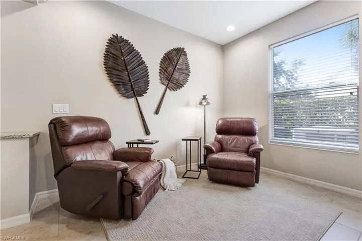 This inviting space features a large window with blinds, light-colored walls, and a light-toned rug