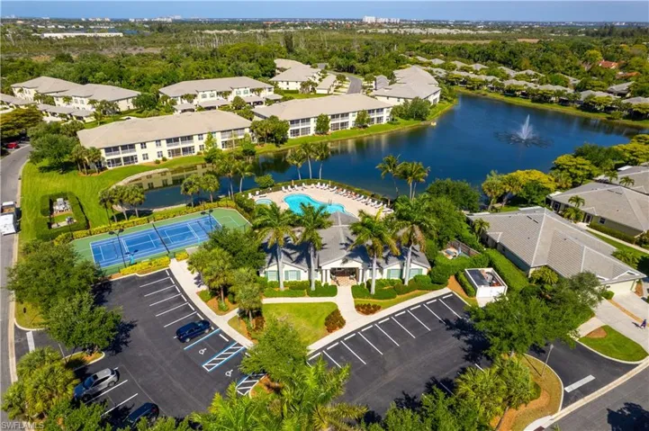 Aerial view of the property and its amenities, including a swimming pool with surrounding lounge chairs, a tennis court, and a parking area