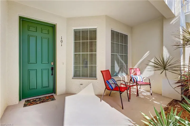 The property features an inviting entryway with a paneled green door, windows with blinds, and an exterior wall with a stucco finish