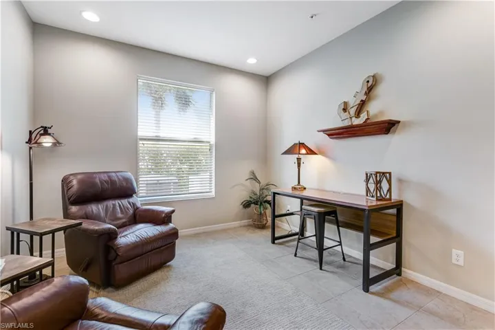 This versatile room features neutral-toned walls, recessed lighting, and a window with blinds providing natural light