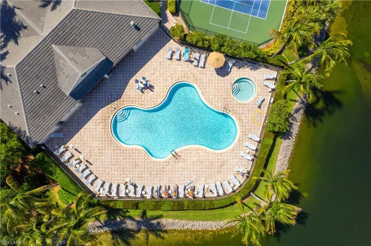 A vibrant outdoor area featuring a swimming pool, a circular spa, and a tennis court