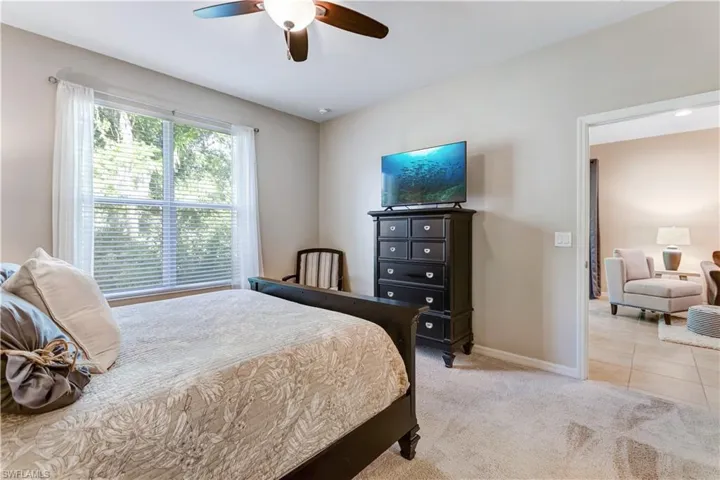 This room features carpeted flooring, a ceiling fan, and a window with blinds and sheer curtains