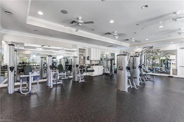The property features an exercise room with a dark floor, various fitness equipment, ceiling fans, and mirrored walls
