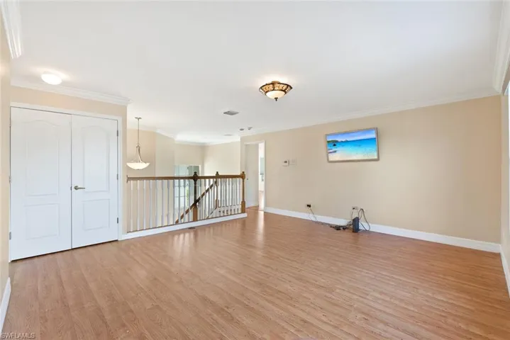 Unfurnished room featuring light wood finished floors, crown molding, and plenty of natural light
