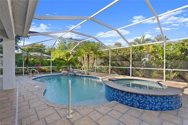 View of pool featuring a sunroom, a pool with connected hot tub, a patio, and a lanai