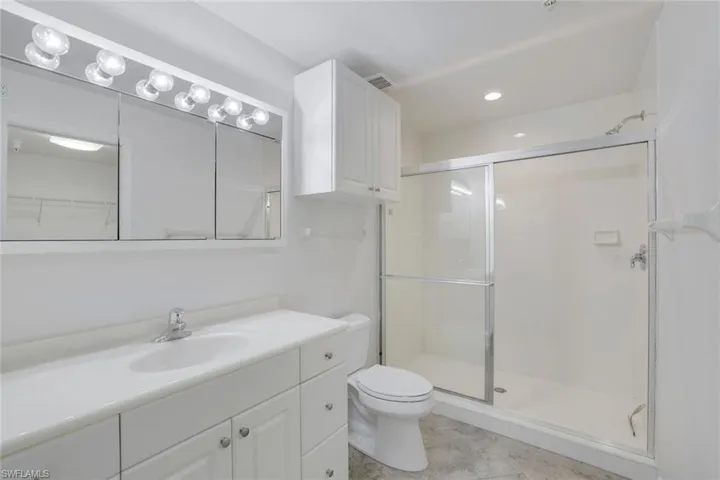 Bathroom featuring toilet, vanity, and walk in shower