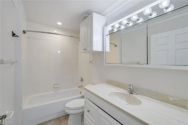 Full bathroom with tiled shower / bath combo, vanity, tile patterned flooring, and toilet