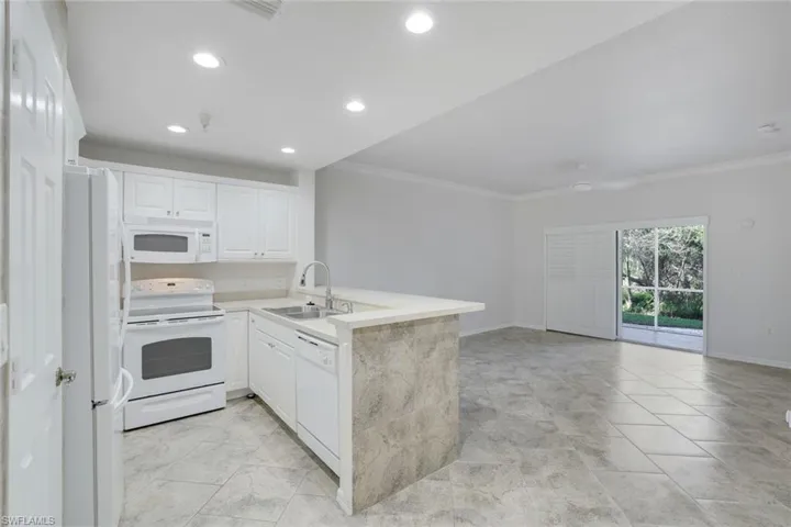 Kitchen featuring sink, white appliances, ornamental molding, white cabinets, and kitchen peninsula