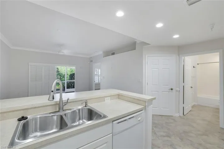 Kitchen with crown molding, sink, white cabinets, and white dishwasher