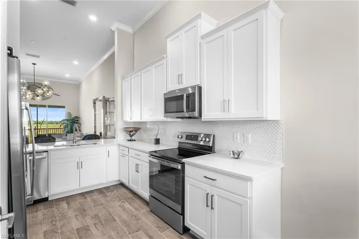 Kitchen featuring stainless steel appliances, decorative backsplash, white shaker cabinetry