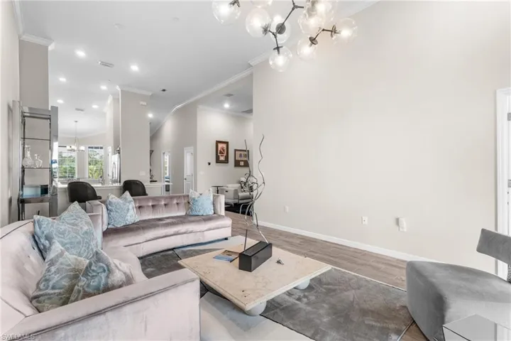 Living area featuring a chandelier, ornamental molding, wood finished floors, and recessed lighting
