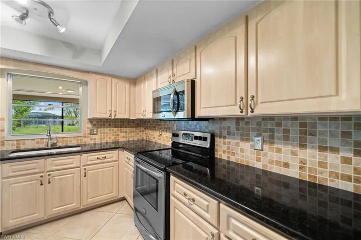 Kitchen featuring appliances with stainless steel finishes, rail lighting, sink, light tile floors, and light brown cabinets