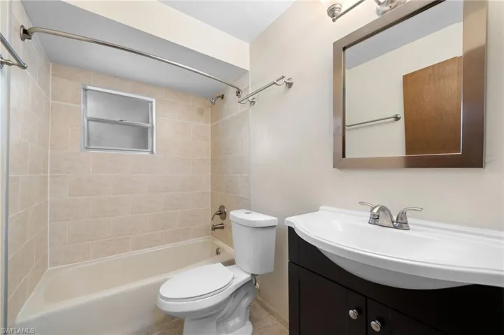 Full bathroom featuring tile flooring, vanity, toilet, and tiled shower / bath combo