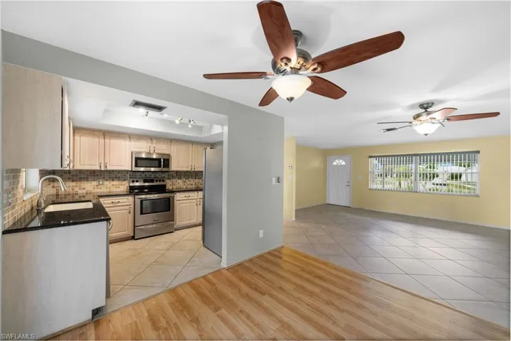Kitchen with backsplash, ceiling fan, appliances with stainless steel finishes, sink, and light tile floors