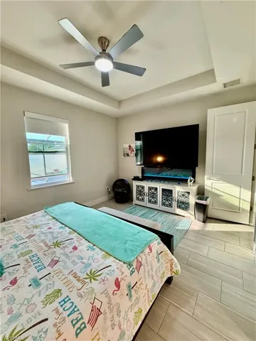 Bedroom featuring a tray ceiling, ceiling fan, and tile finish floors