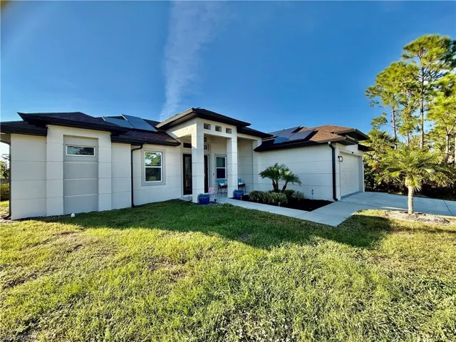 Prairie-style home with roof mounted solar panels, a front lawn, a garage, and driveway