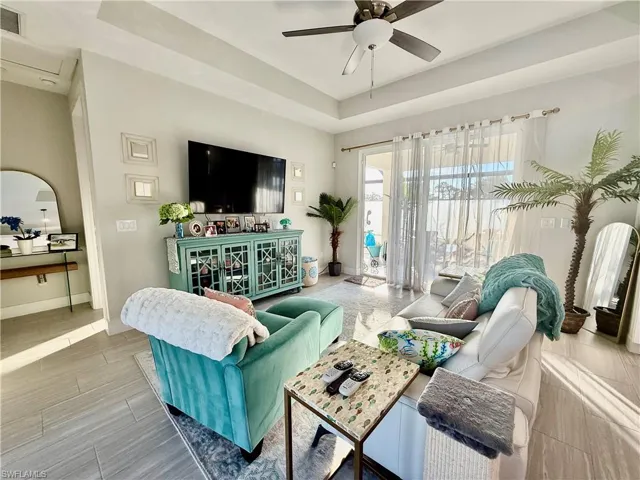 Living area featuring a raised ceiling, ceiling fan, and wood finish floors