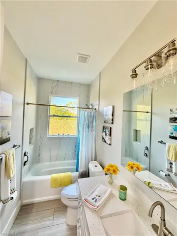 Bathroom featuring vanity, shower / bath combination with curtain, and gray wood-style tile floors
