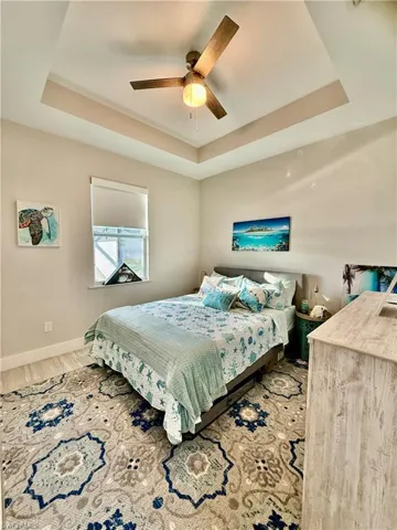 Bedroom with a tray ceiling, tile floors, and ceiling fan