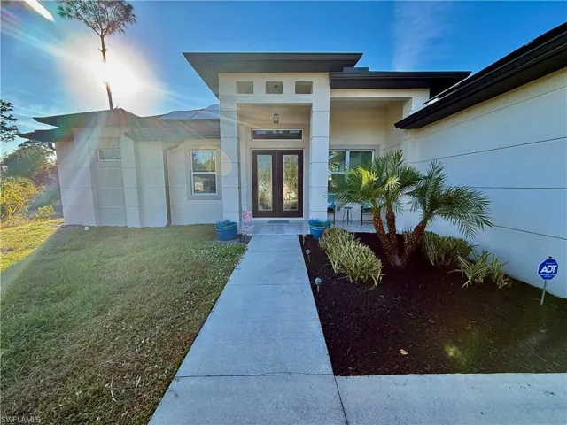 Doorway to property featuring a lawn, stucco siding, and french doors