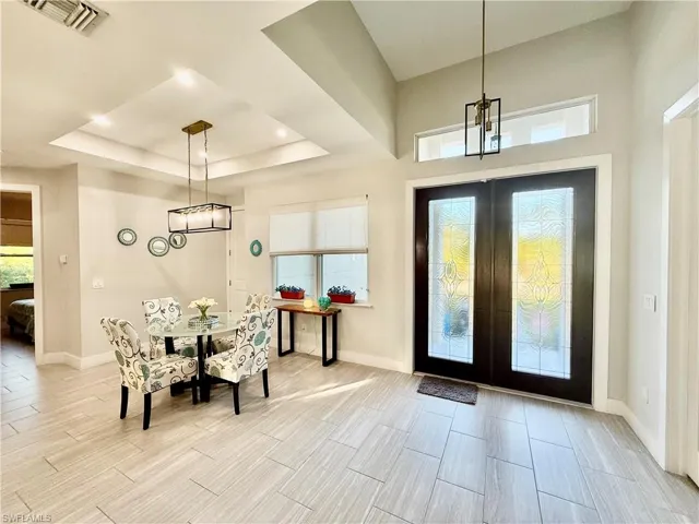 Foyer with double doors, a raised ceiling, and tiled floors