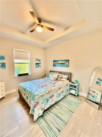 Bedroom featuring a raised ceiling, a ceiling fan, and gray wood-style tile flooring