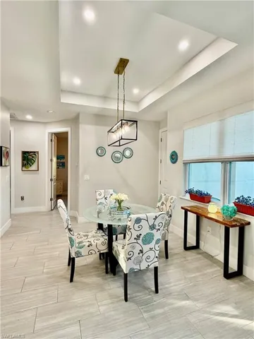 Dining space with a raised ceiling, recessed lighting, tile finish floors, and a chandelier
