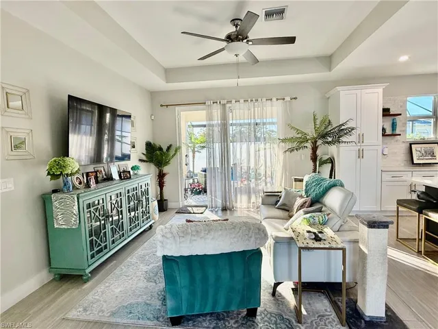 Sitting room featuring a raised ceiling, gray wood-style tile flooring, and ceiling fan