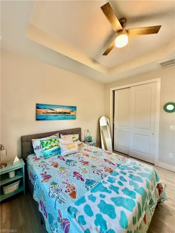 Bedroom with a raised ceiling, a ceiling fan, and a closet