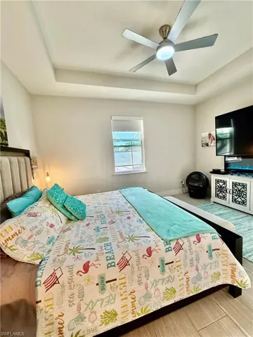Bedroom with a raised ceiling, ceiling fan, and tile finished floors