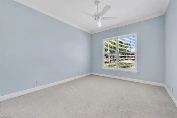 Spare room with light carpet, crown molding, and ceiling fan