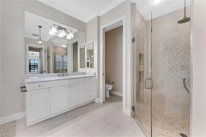 Bathroom with a shower stall, vanity, ornamental molding, and light marble finish floors
