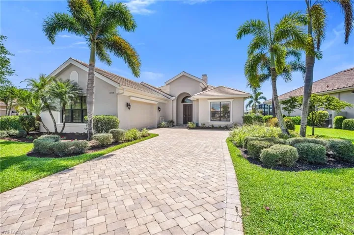 View of front facade featuring decorative driveway, a garage, stucco siding, and a front yard