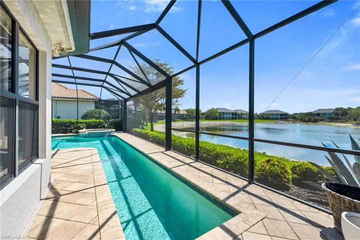 Integrated pool / spa featuring glass enclosure, a sunroom, a water view, and a patio area